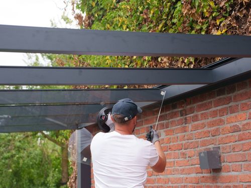 Montage der Glasscheiben an der Wandseite einer Terrassenüberdachung