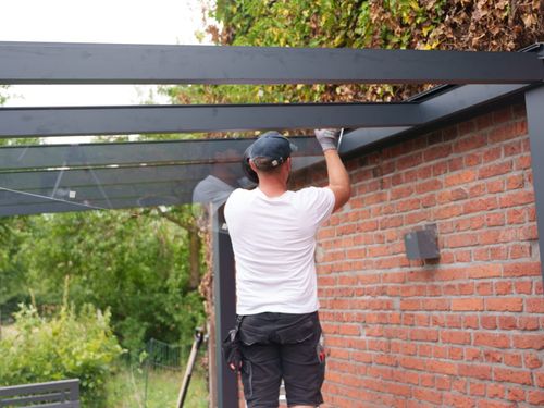 Terrassenüberdachung mit Glasdach an einer Klinkerwand während der Verglasung